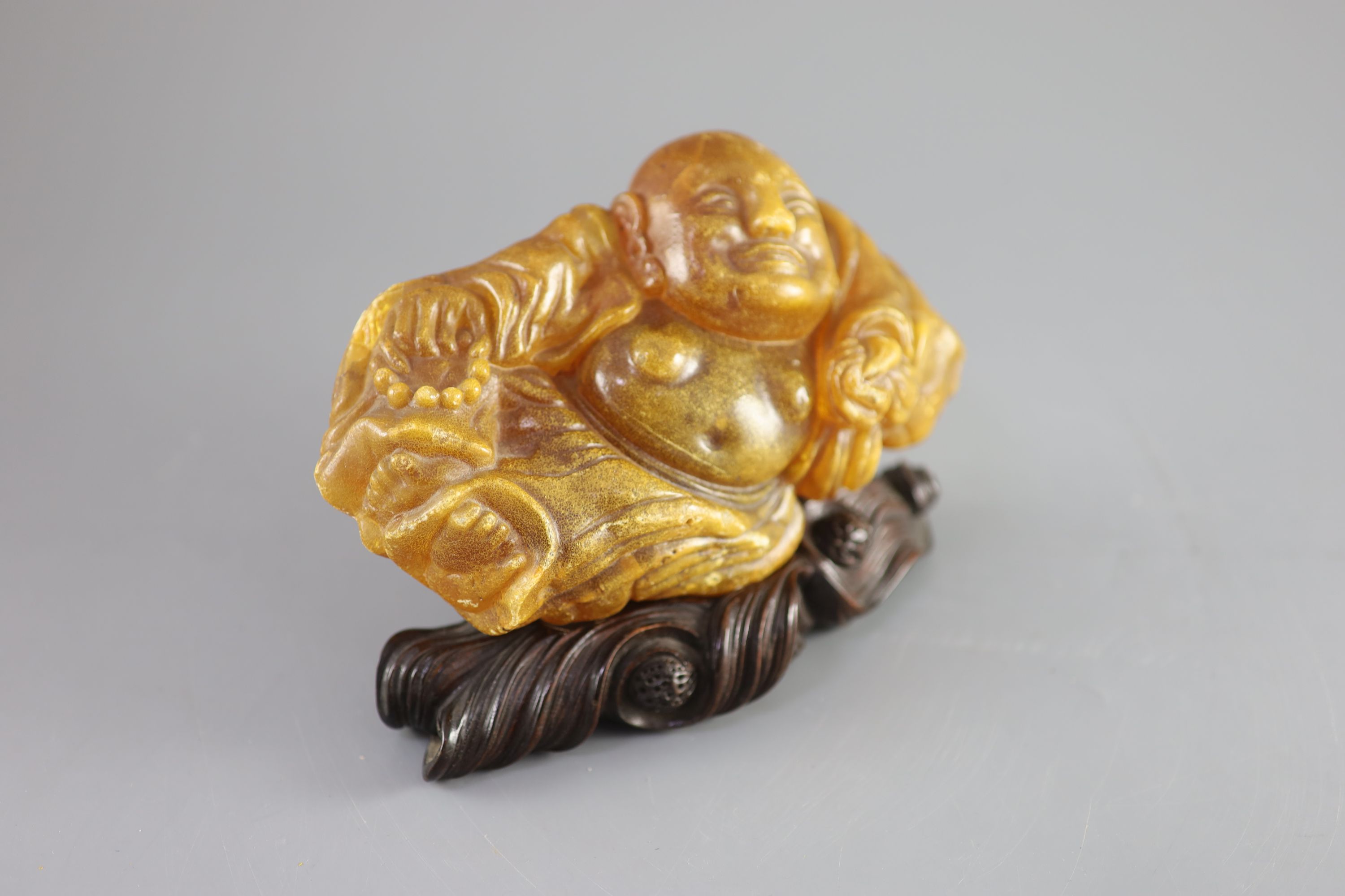 A Chinese amber figure of Buddha, 19th century, width 21.5cm
